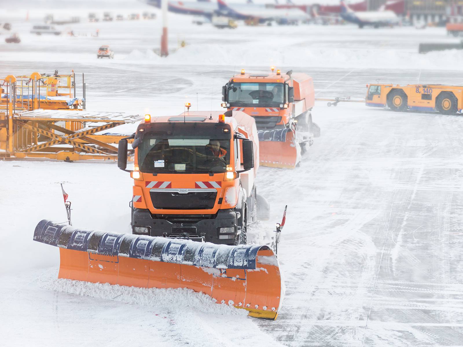 Snowplow removing snow from runways and roads in airport during snow storm